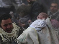 Выжившего ребёнка выносят из разрушенного при авиаударе дома в предместьях Дамаска